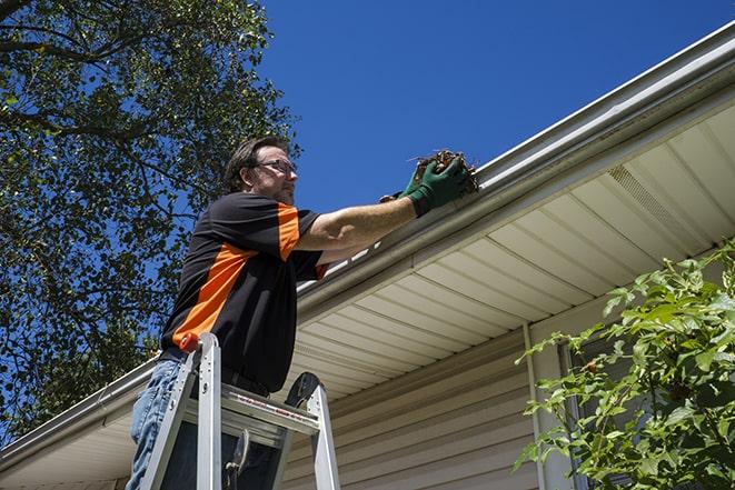 a repair technician inspecting a damaged gutter for necessary repairs in Aguanga